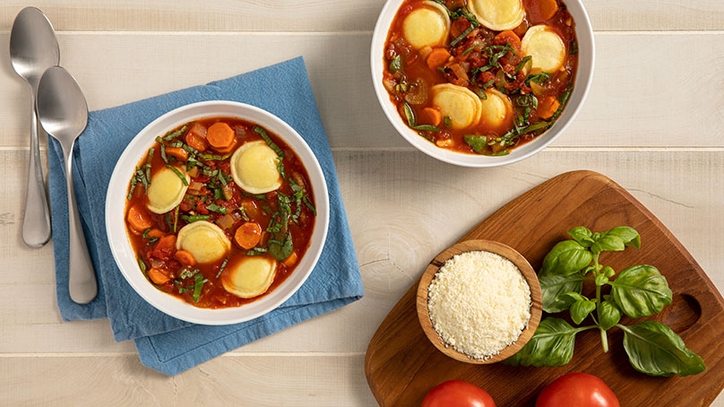 Cheese Ravioli and Vegetable Soup in bowls on kitchen table