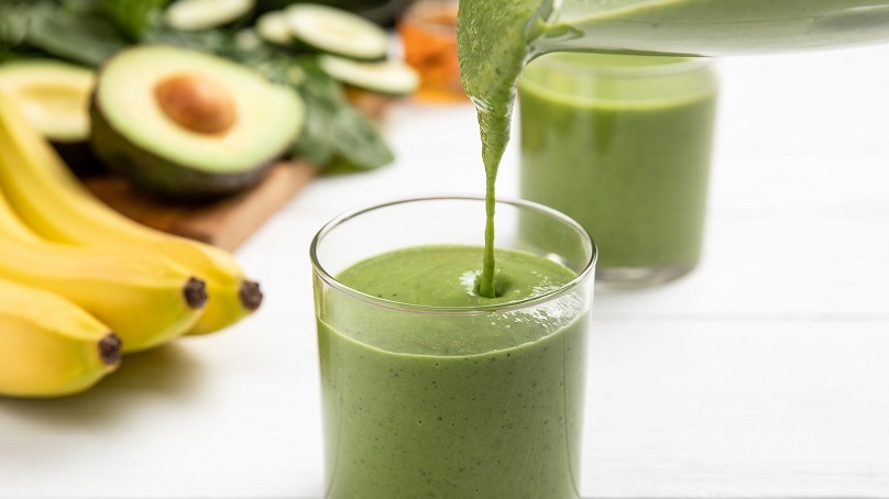 A green goddess smoothie being poured into a glass.