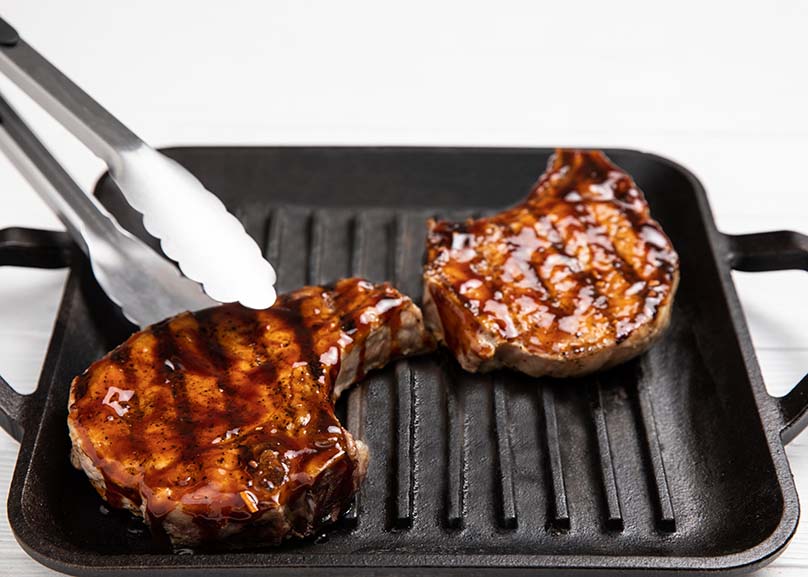 Grill with Honey-Garlic Glazed Pork Chops, Tongs picking up Pork Chop