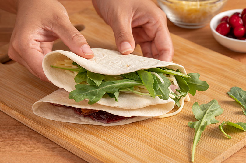 tortilla filled with ingredients being folded by two hands