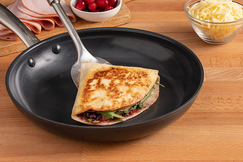 Golden Grilled Leftover Cranberry and Bacon Grilled Cheese Tortilla Wrap being lifted out of pan on spatula