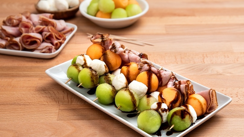 Melon mozzerella skewers on a plate.