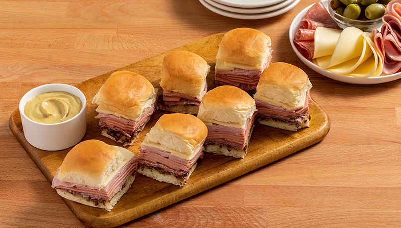 Muffuletta Sliders on wooden serving board near miscellaneous ingredients