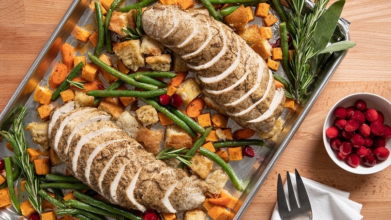 Sheet-Pan Turkey Dinner, sliced turkey, carrots sweet potatoes, green beans, cranberries, sheet pan, fork napkin, wood table