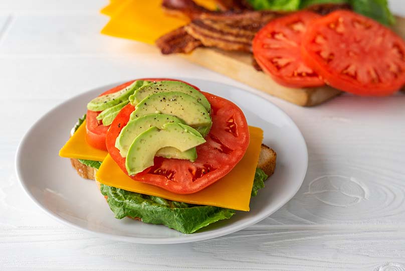 Lettuce, cheese, tomato slices, avocado slice, bread