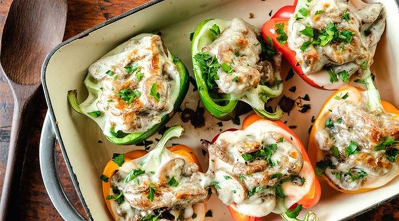 Low-Carb Cheesesteak Stuffed Peppers in baking dish, wooden spoon, wood table