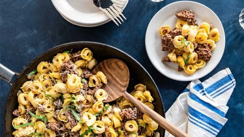 Ground Beef Tortellini Skillet, white plates, forks, blue striped towel, blue tablecloth