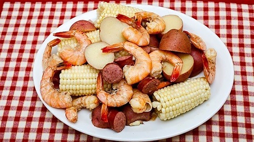 Low Country Shrimp Boil with Smoked Sausage, corn, potatoes, white plate, red checked tablecloth