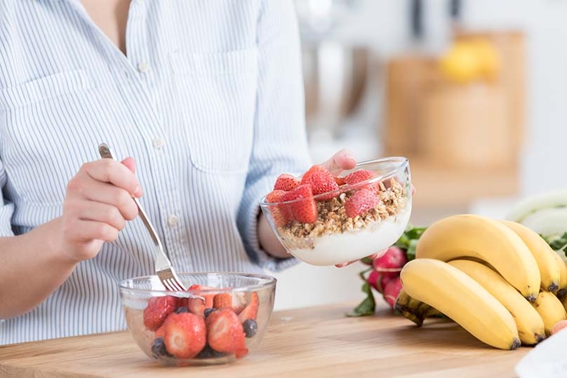 Woman preparing yogurt parfait in kitchen