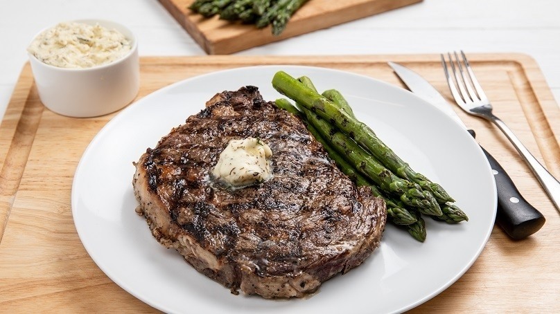 Grilled Steak with Lemon Herb Butter and asparagus, serving bowl of mashed potatoes, steak knife and fork