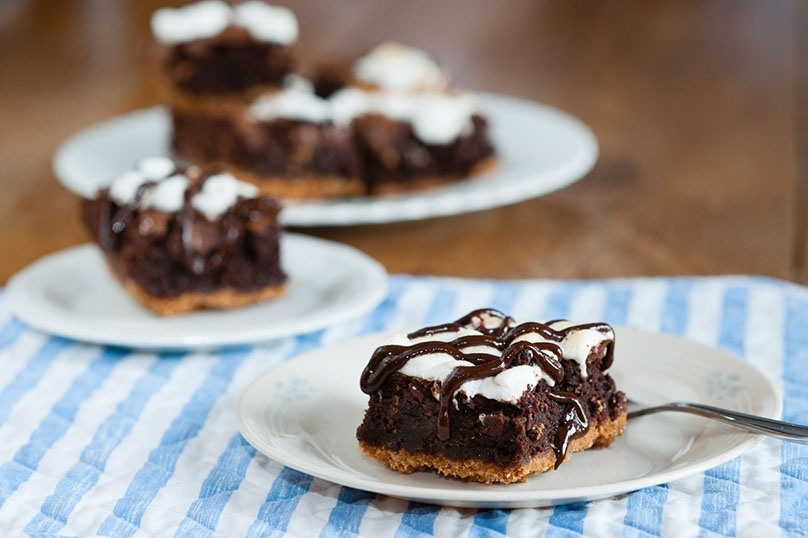 Fudgy S’mores Brownies  on plates, blue and white checked tablecloth, fork, wood table