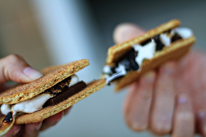 Closeup of two hands holding gooey s'mores