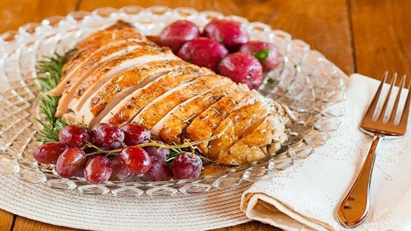 Herb-Roasted Turkey Breast, cranberries, glass plate, placemat, forn, napkin., wood table