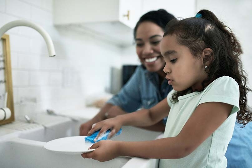 girl washing dishes with Mom