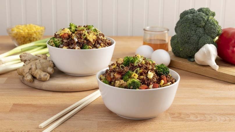 Veggie-Packed Quinoa Fried Rice bowls, spring onions, corn, ginger, eggs, honey, broccoli, garlic, bell pepper, chop sticks, cutting boards, wood table