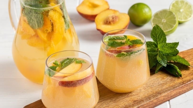 Sparkling Peach and White Wine Spritzers, peaches, limes, mint, board, glasses, pitcher
