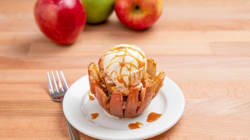 Caramel Walnut Blooming Apple on white plate with fork, fresh apples in background