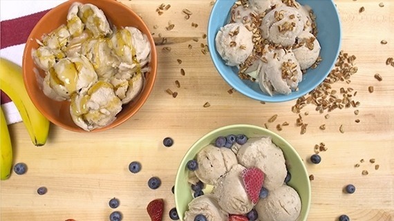 Sugar free banana ice cream in three colorful bowls with granola, caramel, and fruit garnish, fresh berries and bananas, red and white napkin, wood table