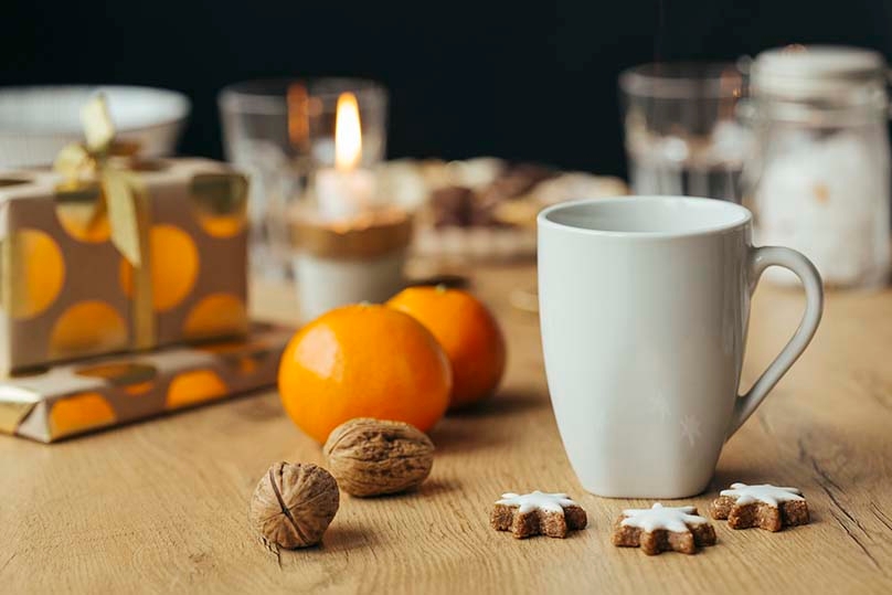 Coffee cup on table with gifts, cookies and candle