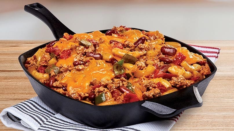One Skillet Chili Mac and Cheese Bake on striped napkin, light wood table