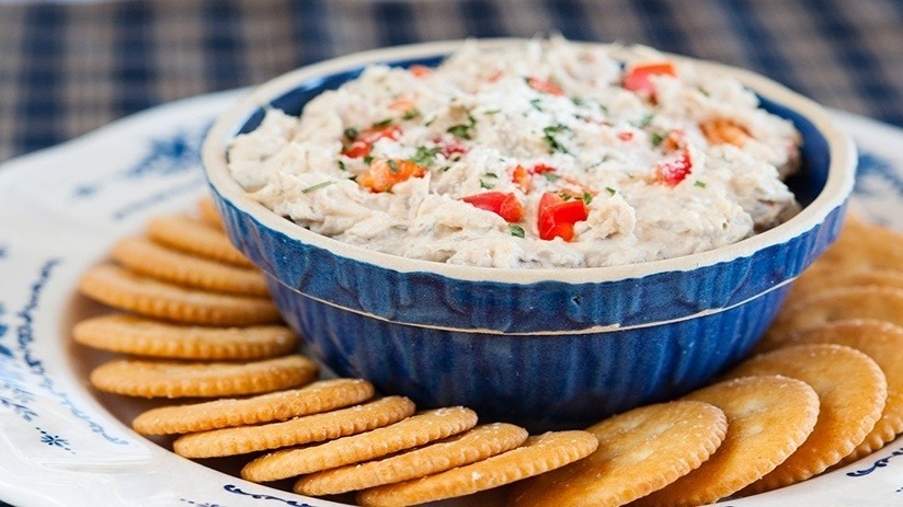 Slow Cooker Crab Dip in blue serving dish surrounded by crackets on plate