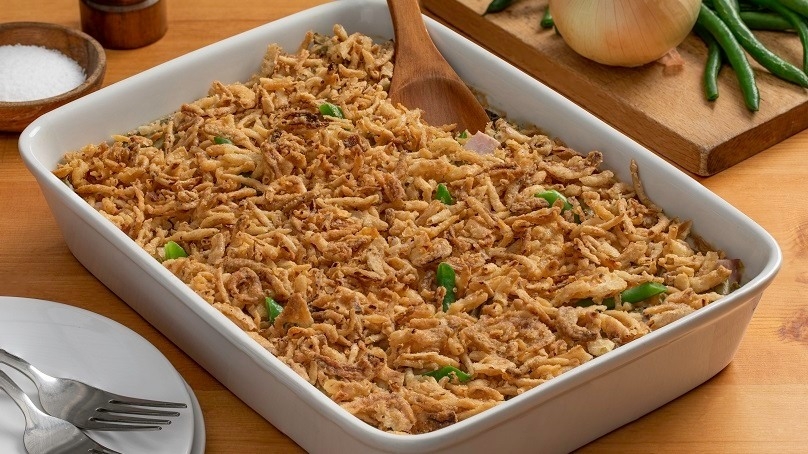 Green Bean and Ham Casserole. in baking pan, plates and silverware, napkins, cutting board with ingredients