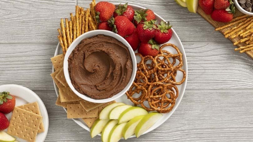 Chocolate Hummus with pretzels, apple slices and strawberries, wood contertop