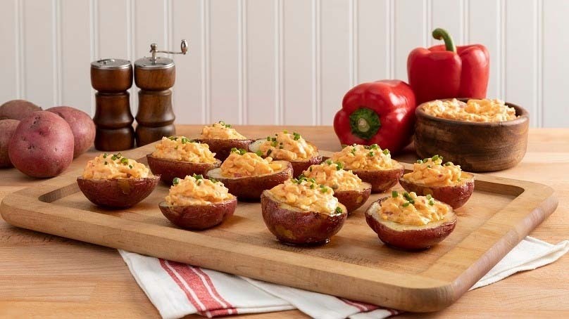 Pimiento Cheese Potato Skin Bites, cutting board, sal shaker and pepper mill, red potatoes, red bell peppers, bowl of pimento cheese, kitchen towel, wood table