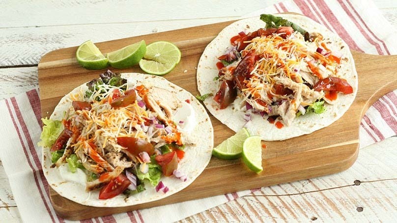 Easy Pulled Chicken Tacos, sliced limes, cutting board, stripped kitchen towel, lught wood table