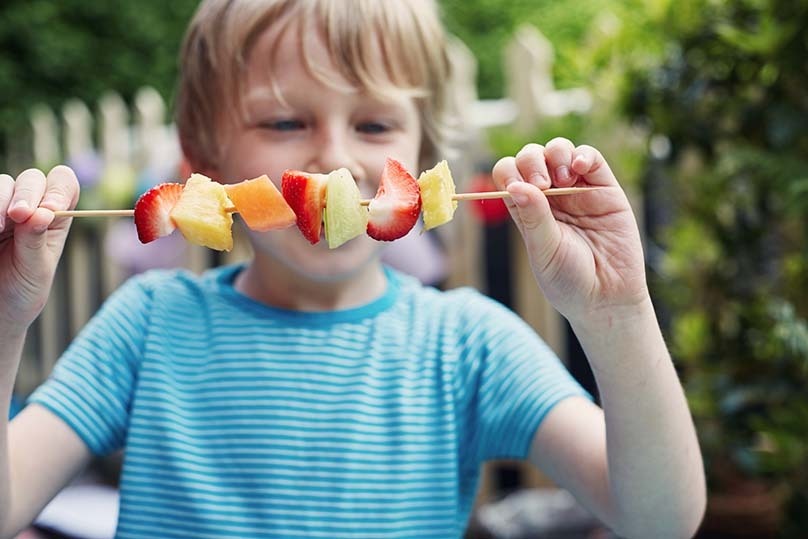 Fruit Skewers, young boy outside, enjoying summer, holding and looking at skewer