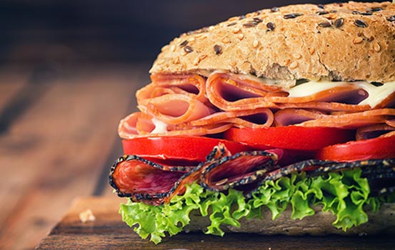 fresh affrodable deli meats and cheeses, deli sandwich, seed roll, tomatoes, lettuce, chopping board